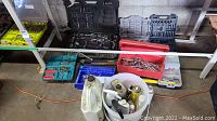 Wide view showing multiple tool cases, trays of wrenches, and a white bucket with spray cans on concrete floor.