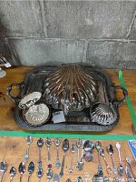 Overview of the complete set showing the large shell serving dish closed along with two smaller shell dishes and the large metal serving tray underneath, with tarnishing visible.