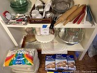 Overall view of baking utensils on shelves including rolling pins, measuring cups, mixing bowls, sifters, plastic wrap, marshmallows, and baking sheets.