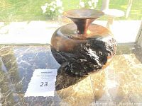 Photo showing the overall shape and surface texture of the redwood bud vase on a marble surface with window lighting.