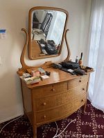 Front angle view of the burl wood vanity with mirror showing items on top and the wood grain finish.