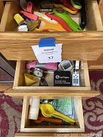 Photo showing drawers filled with colorful peelers, scissors, thermometers, chainmail scrubber, juice reamer, clips, and brushes.