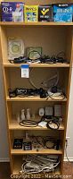 Full shelving unit displaying all electronic accessories included in the lot: Memorex CDs and DVDs, lens wipes, multiple cables, power strips and outlets, night lights.