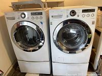 Front view of LG washer and dryer side by side on pedestal bases