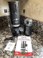 Mueller Ultra-Grind Conical Burr Grinder and Capresso mini grinder together with accessories and manual on kitchen counter.