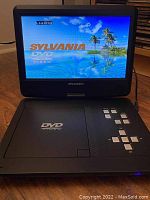 Sylvania portable DVD player powered on showing Sylvania DVD loading screen.