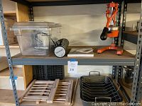 Wide shot of all items on shelving: sous vide bin, juicer, pasta racks, waffle iron plates, roasting pan with rack.