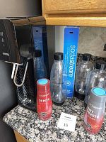 Full view of SodaStream machine with CO2 cylinder box, three bottles, and two soda mixers on a kitchen countertop.