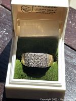 Front view of the ring inside its original white and green King Peerless presentation box, showing full cluster.