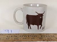 Front view of 1970s ceramic mug with bull illustration and handle visible