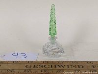 Front view of the perfume bottle with green stopper showing clear detailed glass and intricate cuts.