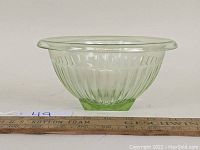 Green Depression glass mixing bowl showing ribbed design and flared lip, placed next to a ruler to provide size reference.