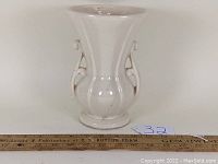 Off white McCoy Pottery vase, frontal view showing flared rim, side handles, and bulbous shape on round foot ring