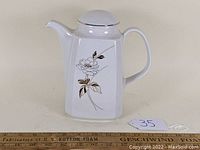 Front view of the Mid Century Bavarian porcelain coffee pot showing white body, floral decoration, gold trim on lid, handle and spout.