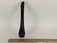 Full view of mid-century swung glass vase, black amethyst color, showing its height relative to a ruler.