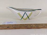 Side view of the mid century gravy boat showing the pattern and shape, placed next to a ruler for scale.