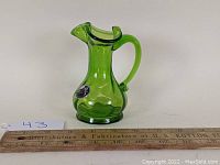 Side view of the green glass Kanawha pitcher showing handle, spout, and original paper label