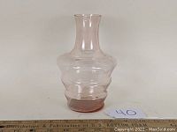 Side front view of pink depression glass carafe on white background with rulers for scale