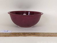 Front side view of the red Pyrex mixing bowl, showing its depth and lip with a ruler for scale.