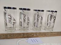 Four vintage Georges Briard sterling overlay bird tumblers at rest, showing detailed bird pattern and silver rims.