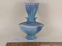 Front and angled view of a blue matte glazed studio art pottery vase with ruffled top and ornamental handles.