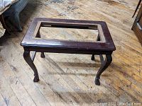 View of the Victorian mahogany piano bench with cane seat frame, showing exposed frame with missing cane and visible wear on mahogany finish.