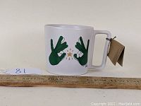 Front view of the white Starbucks mug showing green hand graphic and golden spark/star design.