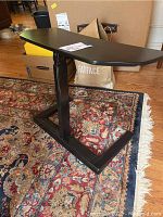 Full side view of the black adjustable height ergonomic keyboard table showing the U-shaped base and height adjustment feature.