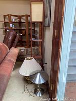 Wooden Danish modern style floor lamp with shelves next to a couch showing lamps on floor