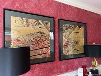 Two large square framed and matted Asian inspired abstract paintings hanging on red textured wall.