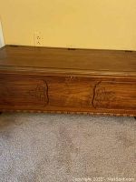Wooden Lane cedar chest closed showing exterior front panel with decorative carving and wood grain.