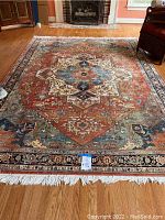 Full view of rug laid on hardwood floor showing overall design and condition