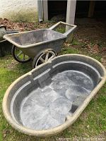 Shows wheelbarrow and Rubbermaid oval pond form from an angle, both positioned on grass with leaf litter around
