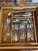 Photo showing bamboo silverware tray with compartments distributing 6 knives, 6 forks, 6 tablespoons, 6 teaspoons, 2 serving spoons, and an extra fork.