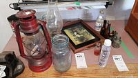 Overview photo of the lot showing various vintage and antique items including lanterns, bottles, tins and framed hunter scene.