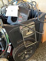 Photo of black plastic utility cart containing battery chargers, power tool batteries, and other small items.