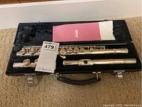 Flute disassembled into headjoint, body, footjoint alongside manual inside black hard case