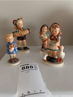 Four Hummel porcelain figurines displayed on a flat surface