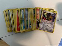 Stack of assorted Pokemon character trading cards showing yellow borders and various illustrations.