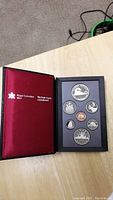 Full view of the red Royal Canadian Mint presentation folder with all eight coins securely displayed in their black foam insert.