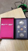 Collector's coin set presented inside case, showing maroon case with Royal Canadian Mint logo and black coin tray with seven coins.