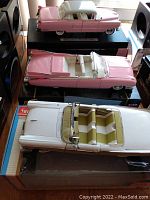 Three die cast car models in 1:18 scale including the 1955 Pink Cadillac, 1957 Ford Fairlane, and a white convertible with tan-green interior.