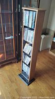 Front view of tall oak grain DVD rack filled with many DVDs.
