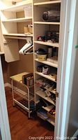 Photo of closet interior showing white plastic coated hangers hanging on rod, a shelving unit with multiple shelves holding a black boombox, tape, hardware containers, paint stain brushes, tape measures, and other assorted small items