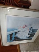 Framed and matted limited edition print showing woman sitting on stairwell behind balustrade.