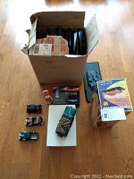 Photo showing all items in the lot including the box marked 'Car Stands' with visible model cars, Texaco gas pump model, boxed model cases, and battery charger.