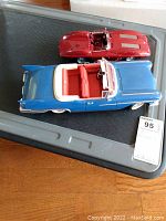 Both model cars on display on a black tray from overhead view.