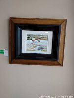 Framed landscape print showing lake and surrounding scenery in wooden frame with black matting
