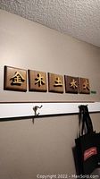 Full set of five wooden plaques mounted on wall, each featuring a distinct Asian character with varying wood stain shades.