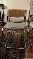 Front view of a single Cesca style cantilever chair showing chrome zigzag base, cane backrest, and cushioned seat with patterned fabric.
